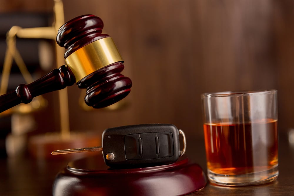 Gavel with a car key and a glass of liquor beside it